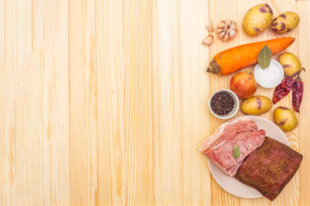 Ingredients for meat stew with potatoes and vegetables. Raw pork fillet, brisket, spices on a stone background, top view, copy spaceの写真素材
