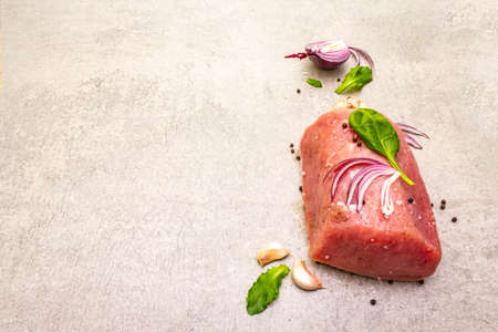 Raw pork tenderloin with vegetables and spices. Cooking meat background, fresh brisket boneless steak on stone background, copy spaceの写真素材