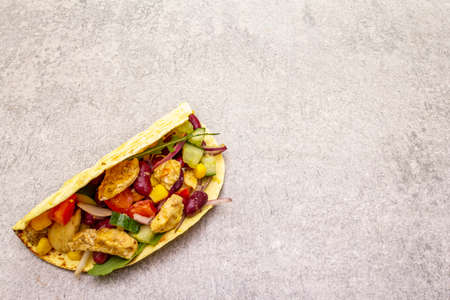 Mexican taco with chicken meat, red beans, fresh vegetables. Latin american food, stone background, copy spaceの写真素材