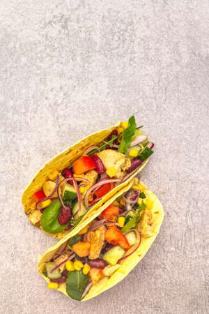 Mexican taco with chicken meat, red beans, fresh vegetables. Latin american food, stone background, close upの写真素材