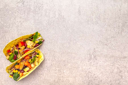 Mexican taco with chicken meat, red beans, fresh vegetables. Latin american food, stone background, copy spaceの写真素材