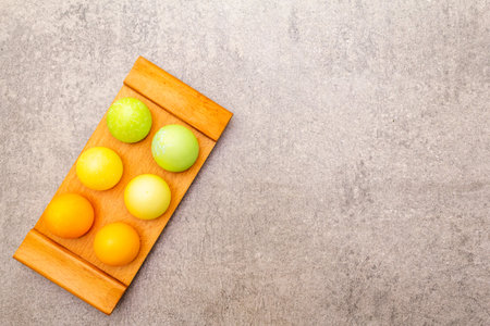 Easter eggs concept on a wooden stand on a stone background, top view, copy space