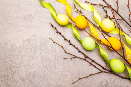 Easter eggs concept willow seals branches with polka dot satin ribbons. On a stone background, copy...