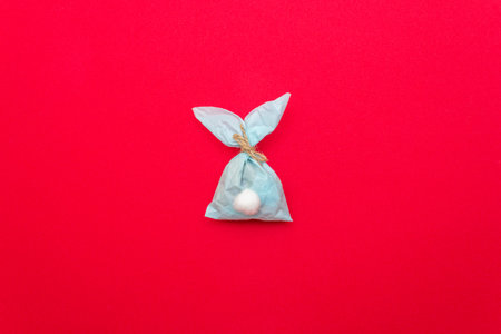 Easter bunny paper gift egg wrapping DIY idea on colorful background. Minimal easter concept, flat...