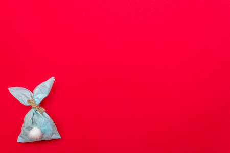 Easter bunny paper gift egg wrapping DIY idea on colorful background. Minimal easter concept, flat lay, copy spaceの写真素材