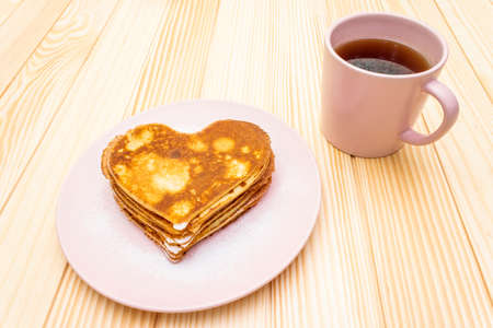Heart shaped pancakes for romantic breakfast with strawberry jam and black tea. Shrovetide (carnival) concept. On wooden background.の写真素材