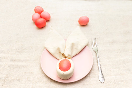 Easter bunny (rabbit) egg concept, table arrangement decoration. Pink (rosy) eggs with plate and...