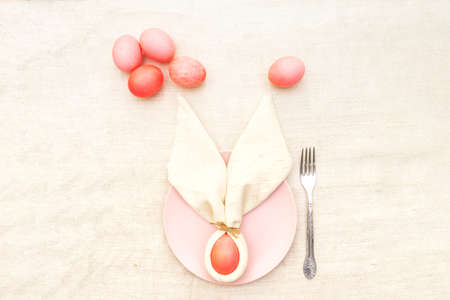 Easter bunny (rabbit) egg concept, table arrangement decoration. Pink (rosy) eggs with plate and...