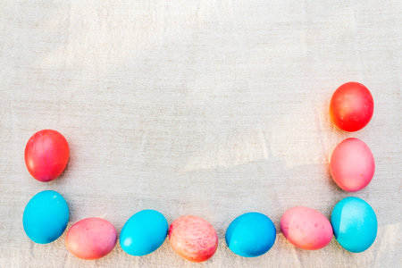 Easter concept pink (rosy) and blue eggs frame. On vintage cloth (linen) background.