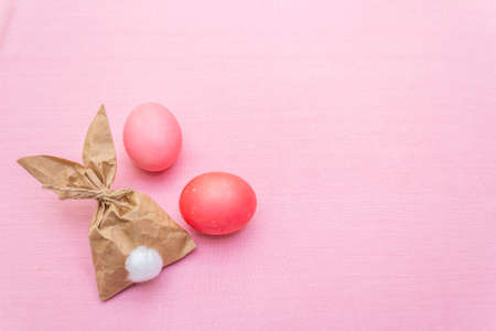 Easter bunny (rabbit) paper gift egg wrapping idea. Handicraft (homemade) concept for children (kids). On pink cloth (linen) background.の写真素材