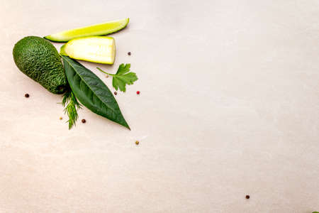 Green vegetables and herbs cooking background. Avocado, avocado leaf, cucumber, zucchini, parsley,...