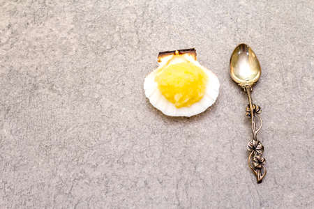 Capelin roe in seashells. Lightly salted caviar snack with silver spoon on a stone background, top view.の写真素材