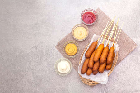 Corn dogs homemade with popular sauces. Traditional American street food. On stone background, top view.の写真素材