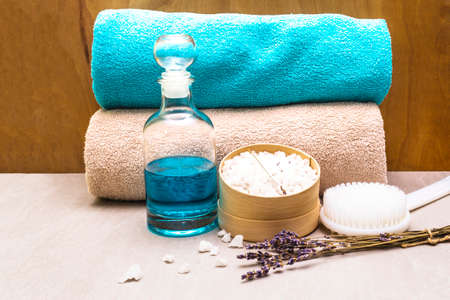 Spa concept, natural ingredients. Bath towels, sea salt with lavender, shower gel, brush. On a stone and wooden background.の写真素材