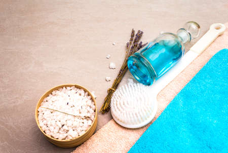 Spa concept, natural ingredients. Bath towels, sea salt with lavender, shower gel, brush. On a stone background.の写真素材
