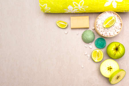 Spa concept, natural ingredients. Bath towel, sea salt with lime, apple, olive and mint soap, sponge. On a stone background, top view.の写真素材