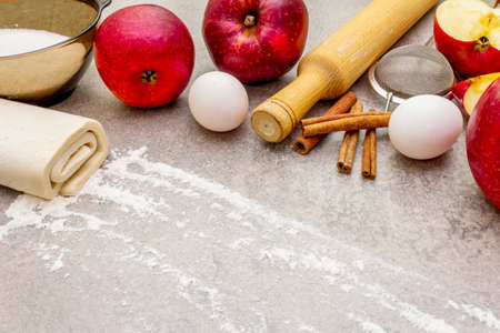 Apple pie ingredients baking concept. Fresh apples with cinnamon, flour, sugar, eggs. Cooking process on stone background, top view.の写真素材