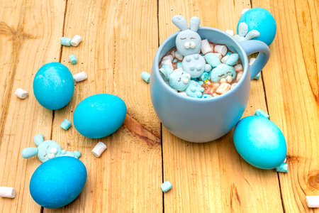 Easter kids hot sweet chocolate or cocoa with funny marshmallow bunny rabbits and easter eggs. On wooden background.の写真素材