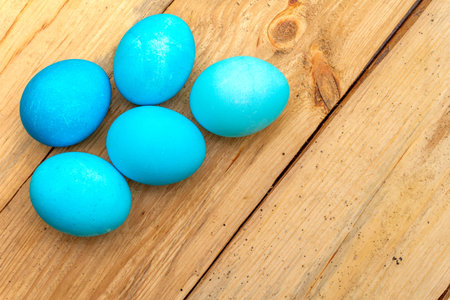 Easter concept with colorful eggs on wooden background, close up, top view, copy space.