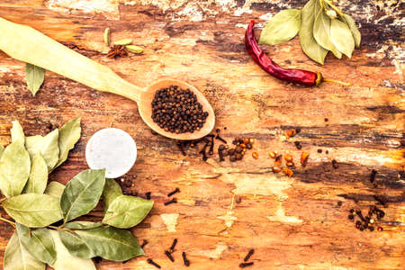 Set of different spices and herbs - black pepper, allspice, hot pepper, bay leaf, salt. On wooden bark background, top view.の写真素材