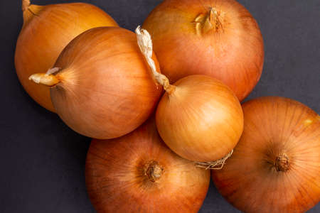 Several large yellow bulbs onion on a black background. Top view.の写真素材