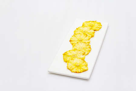Dried slices of pineapple isolated on white background. Healthy eating concept. Rectangular ceramic...