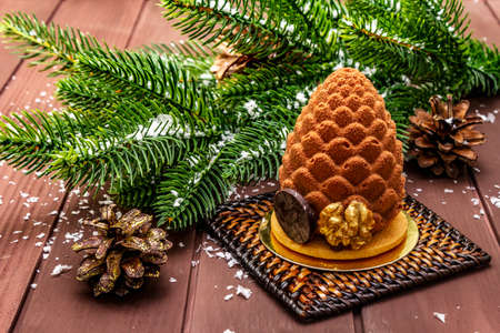 Festive dessert in the shape of a Christmas fir cone. New Year sweet treat concept. Wooden boards background, close upの写真素材