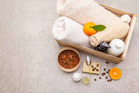 Coffee and tangerine spa concept. Towels, oil, scrub, soap, lotion. Natural ingredient, wooden box. Stone concrete background, copy space, top viewの写真素材