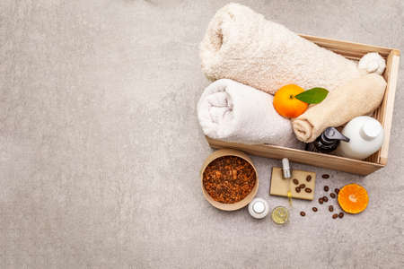 Coffee and tangerine spa concept. Towels, oil, scrub, soap, lotion. Natural ingredient, wooden box. Stone concrete background, copy space, top viewの写真素材