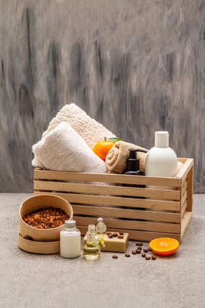 Coffee and tangerine spa concept. Towels, oil, scrub, soap, lotion. Natural ingredient, wooden box. Stone concrete background, copy spaceの写真素材