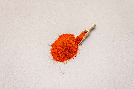 Magyar (Hungarian) brilliant red sweet paprika powder. Traditional ingredient for cooking healthy food. Wooden scoop, stone concrete background, copy space, close upの写真素材