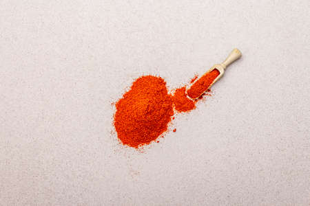 Magyar (Hungarian) brilliant red sweet paprika powder. Traditional ingredient for cooking healthy food. Wooden scoop, stone concrete background, copy space, top viewの写真素材