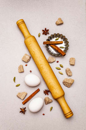 Christmas cooking background, spices, eggs, brown lump sugar, cupcake baking dish and a rolling pin. Light stone concrete background, top view, close upの写真素材