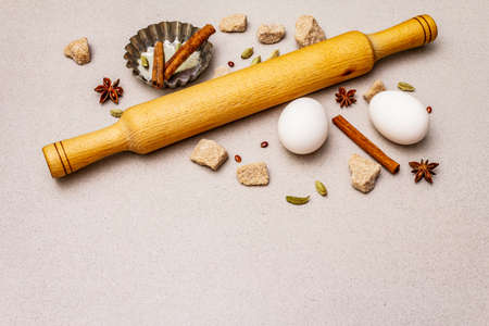 Christmas cooking background, spices, eggs, brown lump sugar, cupcake baking dish and a rolling pin. Light stone concrete background, copy spaceの写真素材