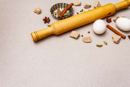 Christmas cooking background, spices, eggs, brown lump sugar, cupcake baking dish and a rolling pin. Light stone concrete background, copy spaceの写真素材