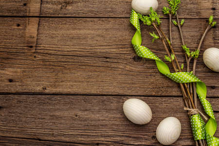 Zero waste Easter concept. Spring twigs with fresh green leaves, wooden eggs, polka dot ribbon. Old vintage wooden boards background, close up, copy space, top viewの写真素材