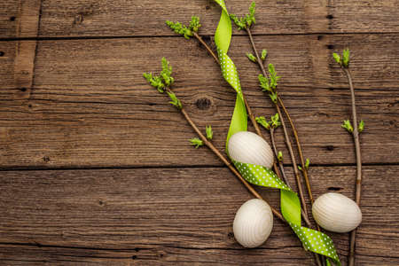 Zero waste Easter concept. Spring twigs with fresh green leaves, wooden eggs, polka dot ribbon. Old vintage wooden boards background, copy space, top viewの写真素材
