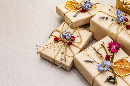 Zero waste gift concept. Valentine Day or Birthday eco friendly packaging. Festive boxes in craft paper with different organic decorations. Stone concrete background, copy space, close upの写真素材