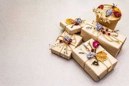 Zero waste gift concept. Valentine Day or Birthday eco friendly packaging. Festive boxes in craft paper with different organic decorations. Stone concrete background, copy spaceの写真素材