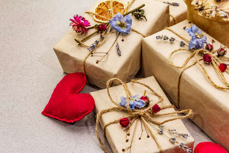 Zero waste gift concept. Valentine Day or Birthday eco friendly packaging. Festive boxes in craft paper with different organic decorations. Stone concrete background, close upの写真素材