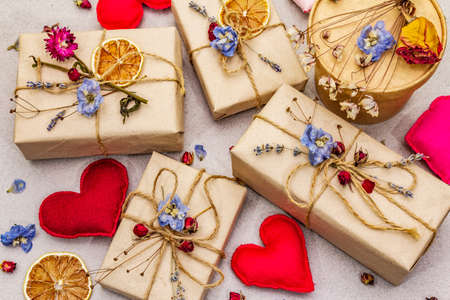 Zero waste gift concept. Valentine Day or Birthday eco friendly packaging. Festive boxes in craft paper with different organic decorations. Stone concrete background, top view, close upの写真素材