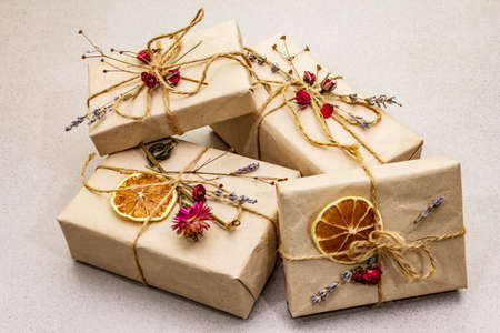 Zero waste gift concept. Valentine Day or Birthday eco friendly packaging. Festive boxes in craft paper with different organic decorations. Stone concrete background, close upの写真素材
