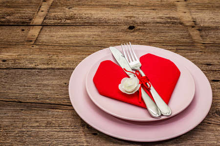 Romantic dinner table. Love concept for Valentine's or mother's day, wedding cutlery. Vintage wooden boards background, copy spaceの写真素材