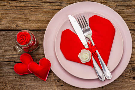 Romantic dinner table. Love concept for Valentine's or mother's day, wedding cutlery. Vintage wooden boards background, top view, close upの写真素材