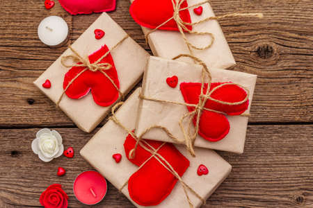 Zero waste gift concept. Valentine Day or Wedding eco friendly packaging. Festive boxes in craft paper with red felt hearts. Vintage wooden background, copy space, top view, close upの写真素材