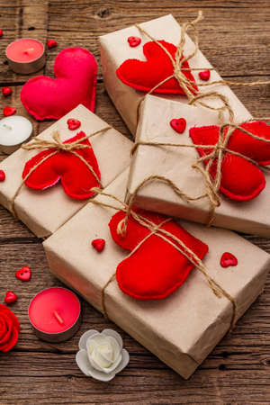 Zero waste gift concept. Valentine Day or Wedding eco friendly packaging. Festive boxes in craft paper with red felt hearts. Vintage wooden background, close upの写真素材