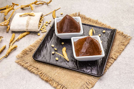 Miso paste, traditional Japanese seasoning. Two types, dark and light brown with dry soya beans. Sackcloth, bag, pods. Stone concrete background, copy spaceの写真素材