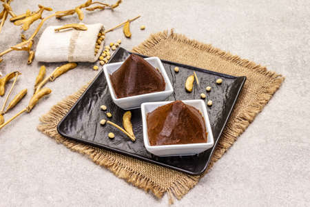 Miso paste, traditional Japanese seasoning. Two types, dark and light brown with dry soya beans. Sackcloth, bag, pods. Stone concrete background, copy spaceの写真素材