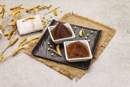 Miso paste, traditional Japanese seasoning. Two types, dark and light brown with dry soya beans. Sackcloth, bag, pods. Stone concrete background, copy spaceの写真素材