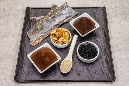 Set of traditional Japanese ingredient for cooking basic dashi broth. Algae kombu and wakame, miso paste, katsuobushi and dry granules. Black ceramic plate, stone backgroundの写真素材